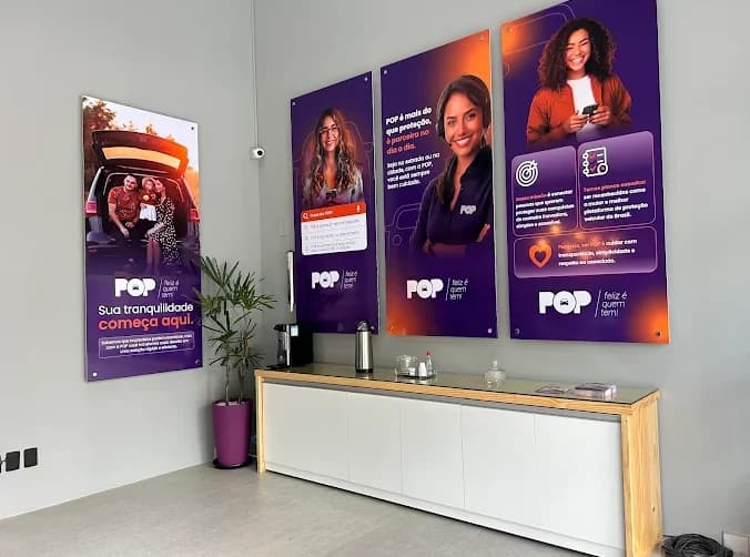 Parede da recepção da loja de Feira de Santana com quatro painéis roxos e laranja, o texto Sua tranquilidade começa aqui e a assinatura feliz é quem tem