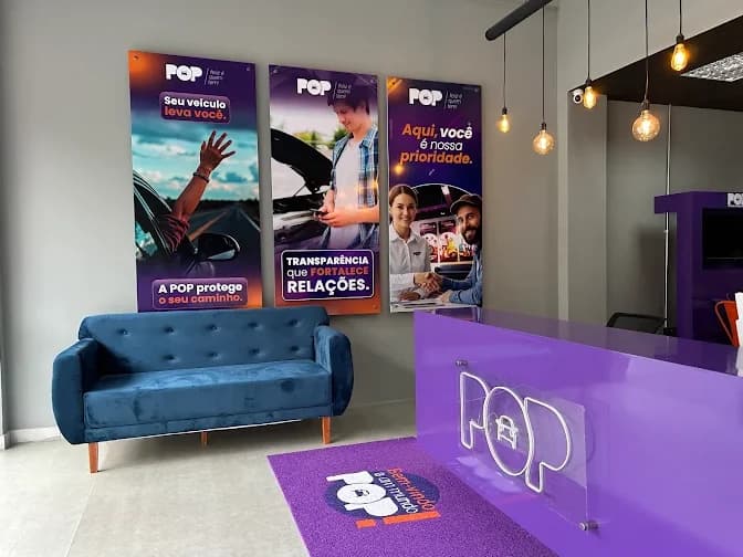 Recepção da loja de Feira de Santana: sofá azul, balcão roxo com a marca POP em neon e painéis em roxo e laranja
